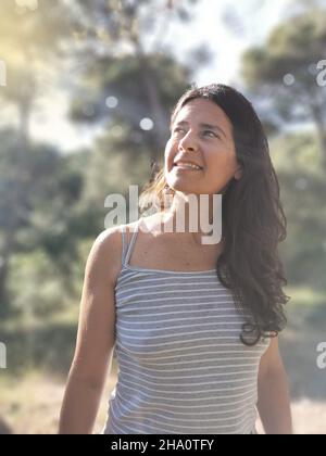 Glückliche spanische Frau mittleren Alters posiert im Wald Stockfoto