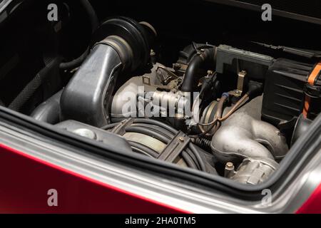 Der Sportwagen-Motor befindet sich unter offener Motorhaube, roter Roadster-Turbomotor Stockfoto