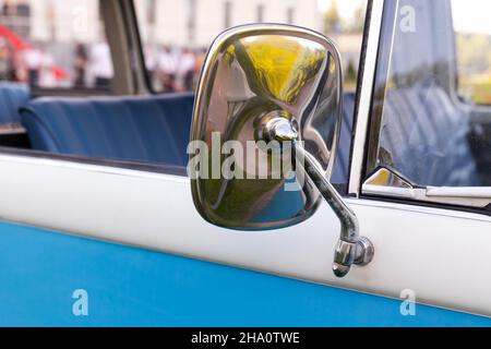 Seitlicher Rückspiegel im verchromten Rahmen. Blauweißes Oldtimer-Fragment, Nahaufnahme mit selektivem Weichfokus Stockfoto