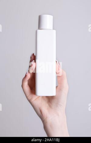 Weiße Flasche für Kosmetika in der Hand einer Frau Stockfoto