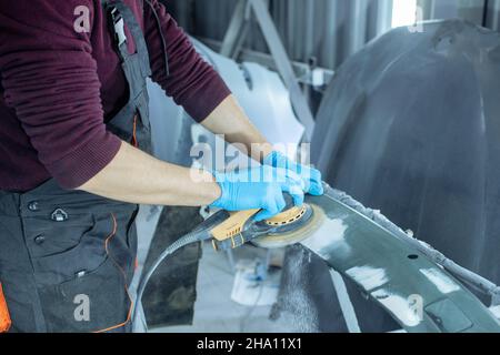 Reparatur der Karosserie durch Verputzen von Naharbeiten nach dem Unfall durch Arbeiten mit Schleifgrundierung vor dem Lackieren. , der Mechaniker reparieren das Auto , mit Stockfoto