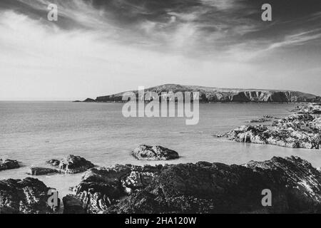 Monochromes Bild einer Strickjacke von der felsigen Küste von Gwbert West wales aus gesehen Stockfoto