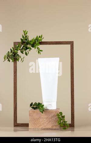 Weiße Kosmetikröhre, steht auf einem rechteckigen beigen Stein Stockfoto
