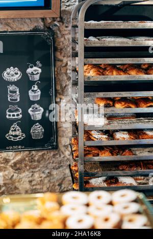 In einer Konditorei liegen süße, mit Puderzucker bestreute Brötchen auf den Regalen Stockfoto