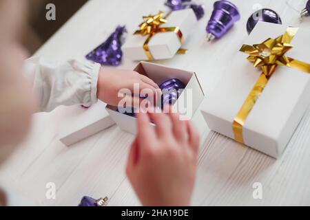 Trendfarbe des Jahres. 2022. Kinderhände sammeln Vintage-Spielzeug sehr peri Farbe in Geschenkverpackung. Verpackung Geschenke für Neujahr und Weihnachten Stockfoto