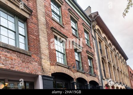 Reihe von traditionellen Backsteingebäuden mit Geschäften im Erdgeschoss in einem Stadtbezirk an einem bewölkten Herbsttag Stockfoto