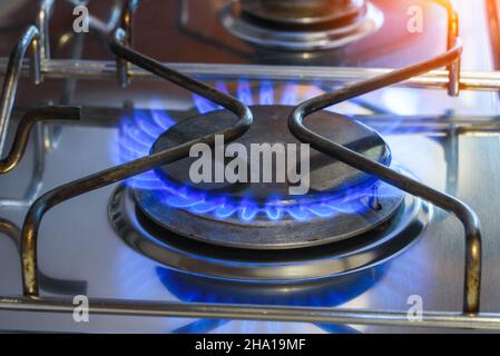 Nahaufnahme eines Gasrings, der auf einem Herdkochfeld mit blauen natürlichen Gasflammen leuchtet Stockfoto