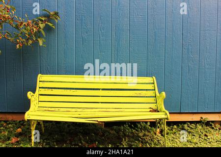 Nahaufnahme einer Holzbank mit einem zerbrochenen Brett, an einer blauen Wand. Stockfoto