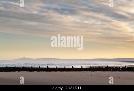 LOSSIEMOUTH, MORAY, SCHOTTLAND - 9. DEZEMBER 2021: Dies ist eine Szene am östlichen Strandbereich des Hafens mit Wellen kurz nach Sonnenaufgang in Lossiemouth, Mo Stockfoto