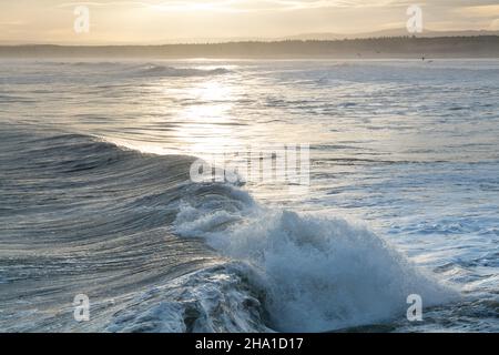 LOSSIEMOUTH, MORAY, SCHOTTLAND - 9. DEZEMBER 2021: Dies ist eine Szene am östlichen Strandbereich des Hafens mit Wellen kurz nach Sonnenaufgang in Lossiemouth, Mo Stockfoto