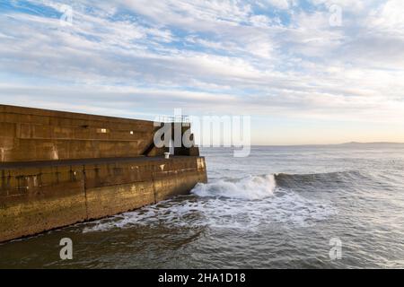 LOSSIEMOUTH, MORAY, SCHOTTLAND - 9. DEZEMBER 2021: Dies ist eine Szene am östlichen Strandbereich des Hafens mit Wellen kurz nach Sonnenaufgang in Lossiemouth, Mo Stockfoto