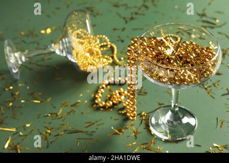 Sektgläser mit goldenen Perlen und Konfetti auf grünem Hintergrund Stockfoto