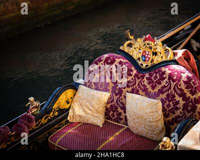 Detail einer leeren Gondel in Venedig (Italien), rote Sitze, gelbe Kissen Stockfoto