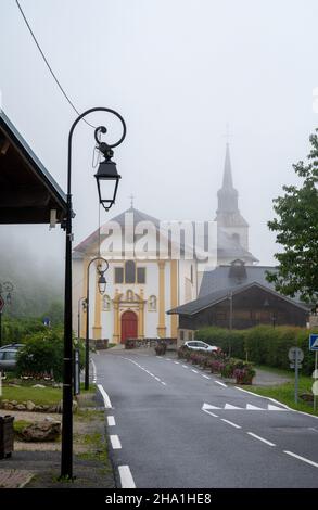 Blick auf die Bergkapelle in einem nebligen kleinen Dorf in der Nähe von Saint-Gervais-les-Bains, Savoyen, Frankreich im Sommer Stockfoto