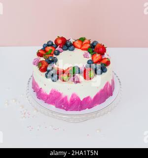 Zarter Kuchen mit frischen Beeren, Erdbeeren und Blaubeeren auf hellem, schlichten Hintergrund Stockfoto