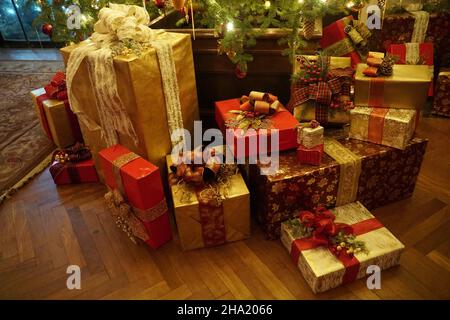 Wunderschön eingewickelt von Geschenken unter dem Weihnachtsbaum mit Lichtern Stockfoto