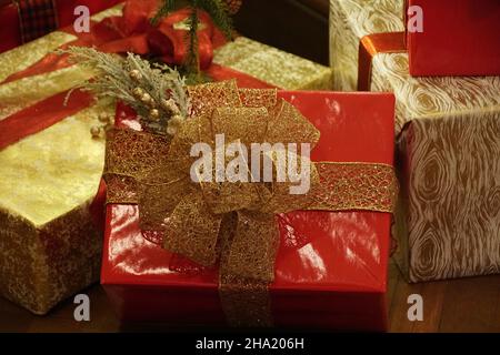 Wunderschön gewickelte rote Schachtel mit goldenen Bändern unter dem Weihnachtsbaum Stockfoto