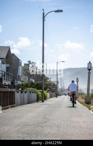 Ältere Amateurmänner in Sommerkleidung reisen auf den Mountainbikes auf dem Fußweg entlang des nebligen Nordwestpazifischen Ozeans und bevorzugen eine aktive Luftröhre Stockfoto