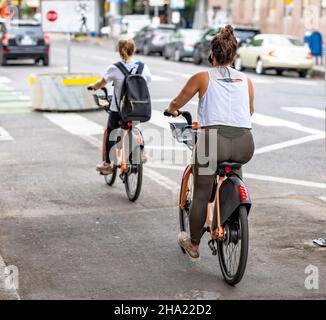 Zwei verschiedene Formen Frauen Amateur-Radfahrer Fahrten von einer Stadt Verleihstation Fahrräder auf dem dedizierten Radweg auf der Straße prefe reisen gemietet Stockfoto