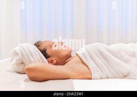 Frau in Handtücher gewickelt nach dem Duschen im Bett liegend. Stockfoto