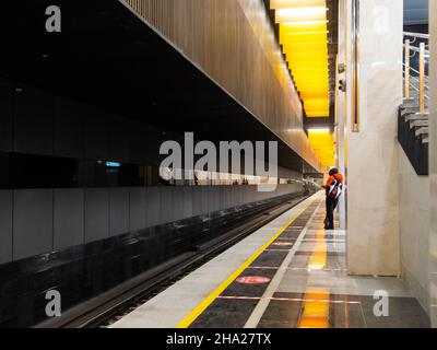 8. Dezember 2021. Moskau. Russland. Auf dem leeren Bahnsteig der Novatorskaya-U-Bahnstation wartet ein einflüchtigerer Passagier auf den Zug. Start der großen Kreislinie der Moskauer Metro. Stockfoto