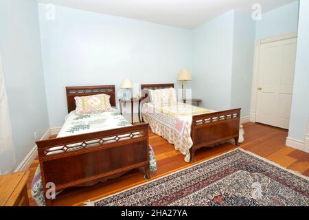 Schlafzimmer im Innenbereich mit zwei Einzelbetten, Nachttisch mit hellen und hellblauen Wänden und Holzfußboden. Stockfoto