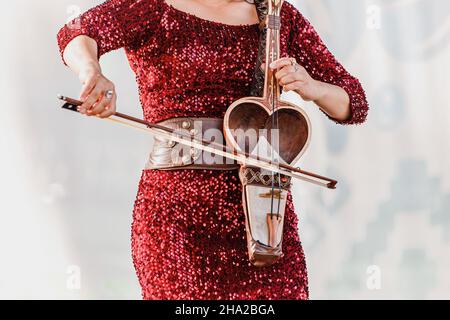 Die Frau tritt auf der Bühne eines Folklorefestivals auf und spielt das Kobyz, ein türkisches Saiteninstrument Stockfoto