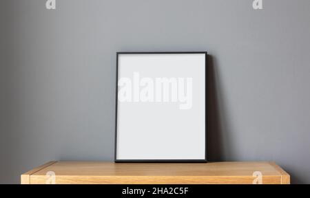 Leerer Rahmen auf Holzregal auf grauem Wandhintergrund Stockfoto