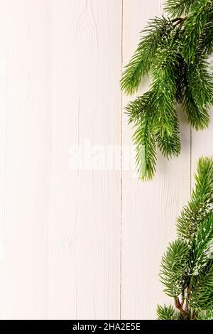 Weihnachtsbaum Äste auf einem hellen hölzernen Hintergrund. Neujahr und Weihnachten Hintergrund. Platz für Text. Vertikales Foto Stockfoto