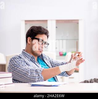 Der junge Student Mann mit der Hand Verletzungen der Vorbereitung für die Prüfungen Stockfoto