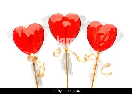 Lollipop. Drei rote herzförmige Lutscher in transparenter Verpackung auf weißem, isoliertem Hintergrund zum Valentinstag. Isolieren. Stockfoto