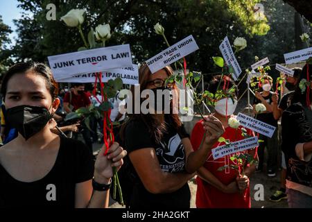 10. Dezember 2021: Menschenrechtsaktivisten tragen Schilder und bieten Blumen an, um an gefallene Helden zu erinnern, anlässlich des Internationalen Menschenrechtstages 73rd in Quezon City, Metro Manila, Philippinen. 10. Dezember 2021. Das Denkmal ehrt die Märtyrer und Helden, die gegen die 21-jährige Diktatur des ehemaligen Präsidenten Ferdinand Marcos kämpften. Kredit: ZUMA Press, Inc./Alamy Live Nachrichten Stockfoto