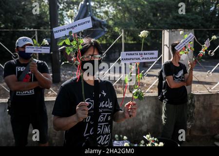 10. Dezember 2021: Menschenrechtsaktivisten tragen Schilder und bieten Blumen an, um an gefallene Helden zu erinnern, anlässlich des Internationalen Menschenrechtstages 73rd in Quezon City, Metro Manila, Philippinen. 10. Dezember 2021. Das Denkmal ehrt die Märtyrer und Helden, die gegen die 21-jährige Diktatur des ehemaligen Präsidenten Ferdinand Marcos kämpften. Kredit: ZUMA Press, Inc./Alamy Live Nachrichten Stockfoto