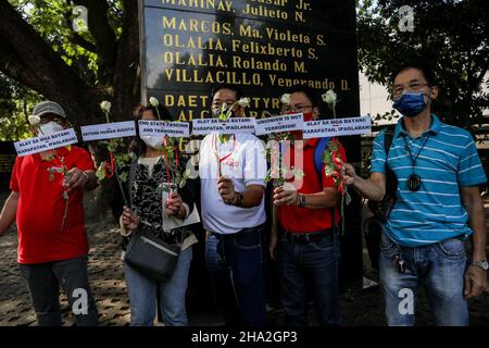 10. Dezember 2021: Menschenrechtsaktivisten tragen Schilder und bieten Blumen an, um an gefallene Helden zu erinnern, anlässlich des Internationalen Menschenrechtstages 73rd in Quezon City, Metro Manila, Philippinen. 10. Dezember 2021. Das Denkmal ehrt die Märtyrer und Helden, die gegen die 21-jährige Diktatur des ehemaligen Präsidenten Ferdinand Marcos kämpften. Kredit: ZUMA Press, Inc./Alamy Live Nachrichten Stockfoto