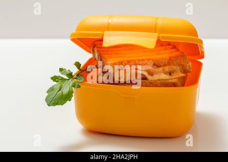Gelbe Lunchbox mit gerösteten Brotscheiben, Käse. Stockfoto