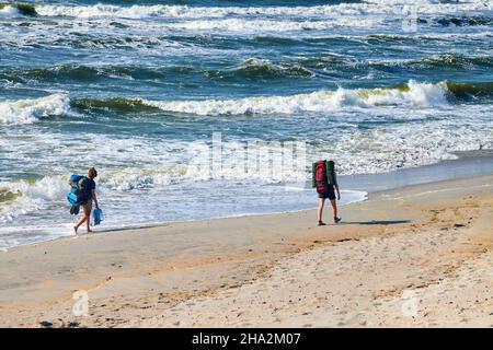 Zwei junge Frauen, die auf dem Meer unterwegs sind. Mädchen Reisende mit großen Rucksäcken erkunden neue Route, schöne Ostsee Hintergrund. Weibliche tra Stockfoto