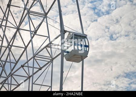 Nahaufnahme der Beobachtungsradankabine, blauer Himmel im Hintergrund. Weißer PKW von großem Riesenrad im Vergnügungspark, Blick vom Boden. Vogelperspektive bei Stockfoto