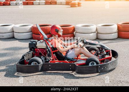 Fröhlicher Teenager, der ein Go-Kart-Auto um das Cartodrome fährt. Hobbys und Extremsport für ein Kind und die Erfüllung eines Traums Stockfoto