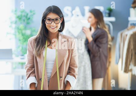 Junge nette Schneiderin mit Maßband Stockfoto