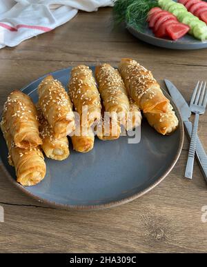 Ein klassischer türkischer Frühstückstisch ist aus nächster Nähe zu sehen. Köstliche hausgemachte Frühlingsrollen und frische Tomaten und Gurken stehen auf Tellern. Stockfoto