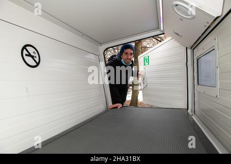 Ulm, Deutschland. 10th Dez 2021. Designer Florian Geiselhart blickt auf ein Ulmer Nest am Karlsplatz. Diese Schlafpoden, die von innen verschlossen werden können, dienen als geschützter Schlafplatz für Obdachlose. In den Wintermonaten werden zwei Nester als Schutz vor Kälte betrieben. Quelle: Stefan Puchner/dpa/Alamy Live News Stockfoto