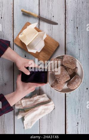 Das Konzept der Bestellung und Lieferung von Lebensmitteln im Internet. Der Typ bestellt Lebensmittel in der Anwendung auf dem Smartphone Stockfoto