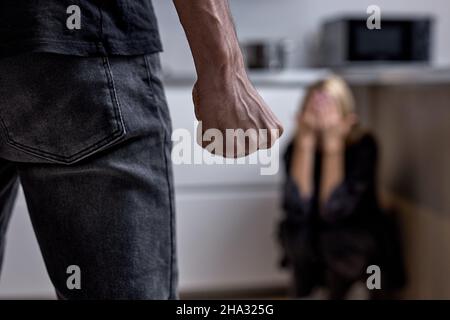 Der alkoholische Ehemann schlägt die Frau mit der Faust. Frau bedeckt sich mit Händen. Gewalt in der Familie. Cropped Mann greift Frau, häusliche Gewalt. Betrunkener Husba Stockfoto