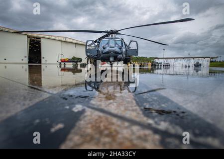 Ein HH-60G Pave Hawk sitzt vor einem Hangar auf dem Kadena Air Base, Japan, 29. November 2021. Viele Faktoren wurden von den 33rd Mitgliedern des Rettungsgeschwaders während ihrer Teilnahme am Turkey Shoot berücksichtigt, einschließlich des Wetters, das die Anpassungsfähigkeit der Einheit bei Änderungen der Flugpläne und Flugmanöver testete. (USA Luftwaffe Foto von Airman 1st Klasse Cesar J. Navarro) Stockfoto