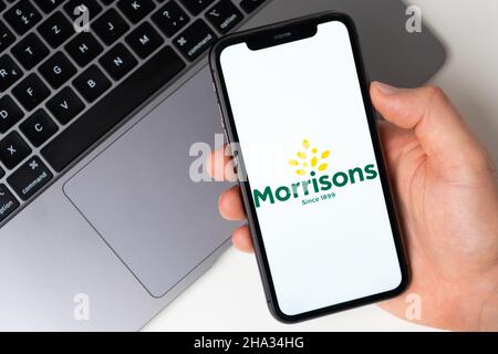 Morrisons die Anwendung ist im Smartphone geöffnet. Der Mann hält ein Mobiltelefon in der Hand, die Unternehmensanwendung ist auf dem Bildschirm geöffnet. Sicheres Online-Shopping. November 2021, San Francisco, USA Stockfoto