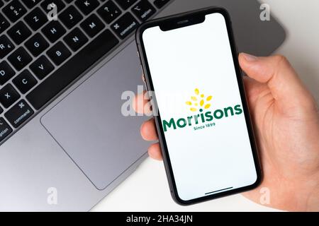 Morrisons die Anwendung ist im Smartphone geöffnet. Der Mann hält ein Mobiltelefon in der Hand, die Unternehmensanwendung ist auf dem Bildschirm geöffnet. Sicheres Online-Shopping. November 2021, San Francisco, USA Stockfoto