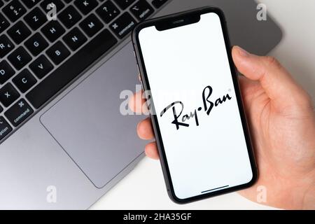 Ray Ban die Anwendung ist im Smartphone geöffnet. Der Mann hält ein Mobiltelefon in der Hand, die Unternehmensanwendung ist auf dem Bildschirm geöffnet. Sicheres Online-Shopping. November 2021, San Francisco, USA