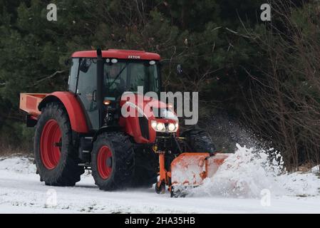 Pultusk, Polen - 10. Dezember 2021: Schneeräumung von einer Landstraße mit einem Traktor mit Schneepflug. Stockfoto