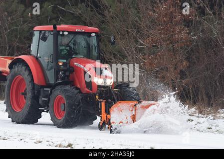 Pultusk, Polen - 10. Dezember 2021: Schneeräumung von einer Landstraße mit einem Traktor mit Schneepflug. Stockfoto