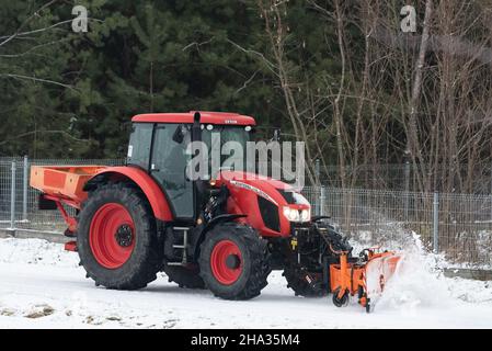 Pultusk, Polen - 10. Dezember 2021: Schneeräumung von einer Landstraße mit einem Traktor mit Schneepflug. Stockfoto